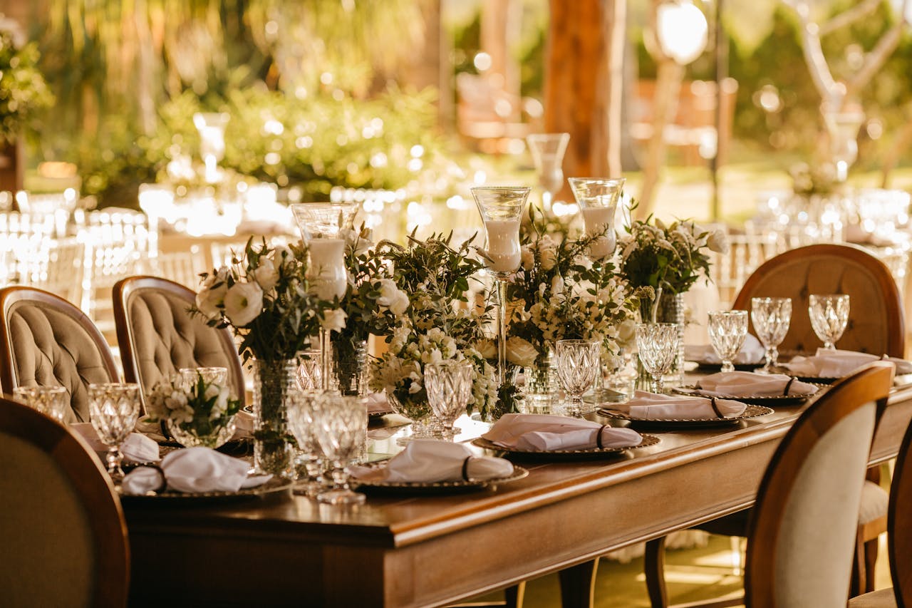 Services Elegant outdoor wedding reception with beautifully set table, flowers, and glasses.