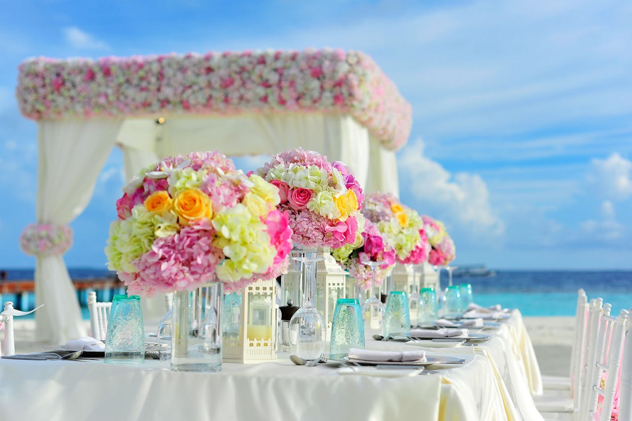 Services Beautiful seaside wedding setup with floral arrangements and pastel colors on a sunny day.